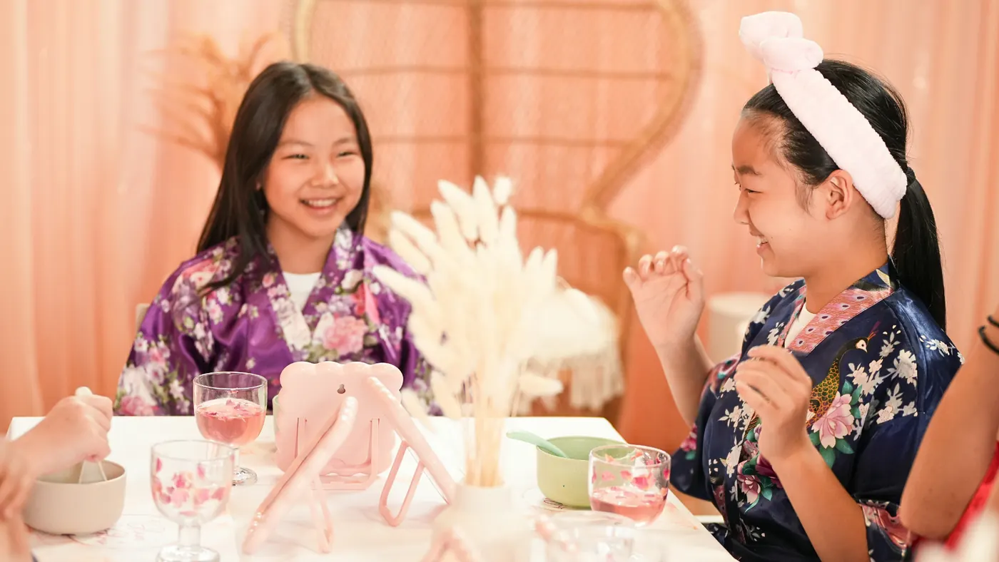Two girls in robes laughing at the Glam & Glow spa table