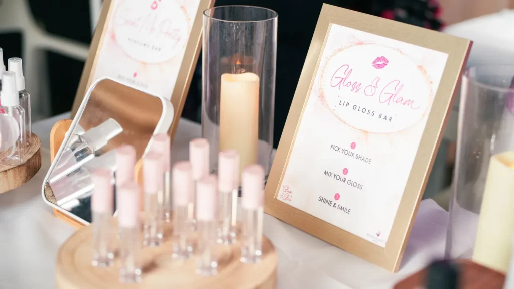 Gloss and Glam lip gloss bar with empty tubes and a framed sign